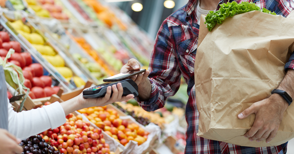 Tips om gezond en goedkoop te eten, iemand rekent af met mobiel bij de groenteboer